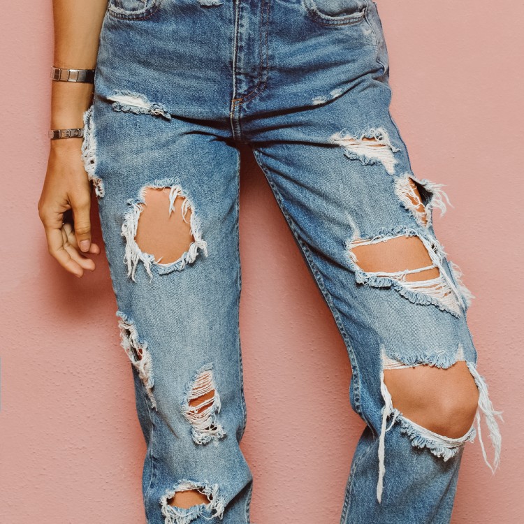 Lady in fashionable ripped Jeans stands in pink wall by Evgeniya Porechenskaya © Shutterstock Inc. All rights reserved. 